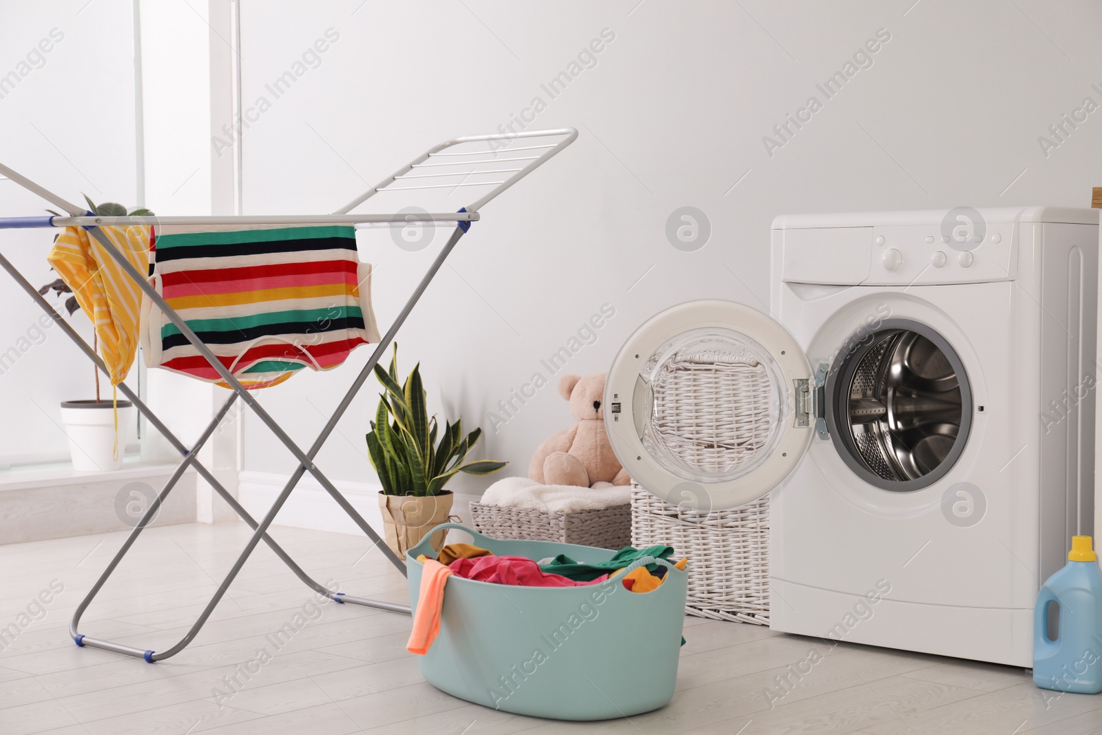 Photo of Clothes drying rack, laundry basket and washing machine indoors