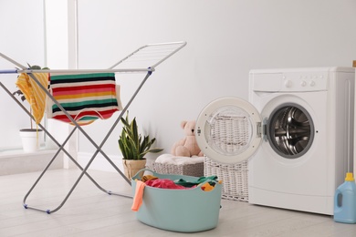 Photo of Clothes drying rack, laundry basket and washing machine indoors