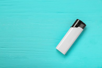 Photo of Stylish small pocket lighter on turquoise wooden background, top view. Space for text