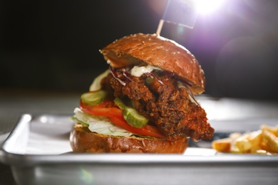 Photo of Tray with delicious burger on dark background