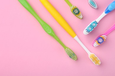 Photo of Many different toothbrushes on pink background, flat lay. Space for text