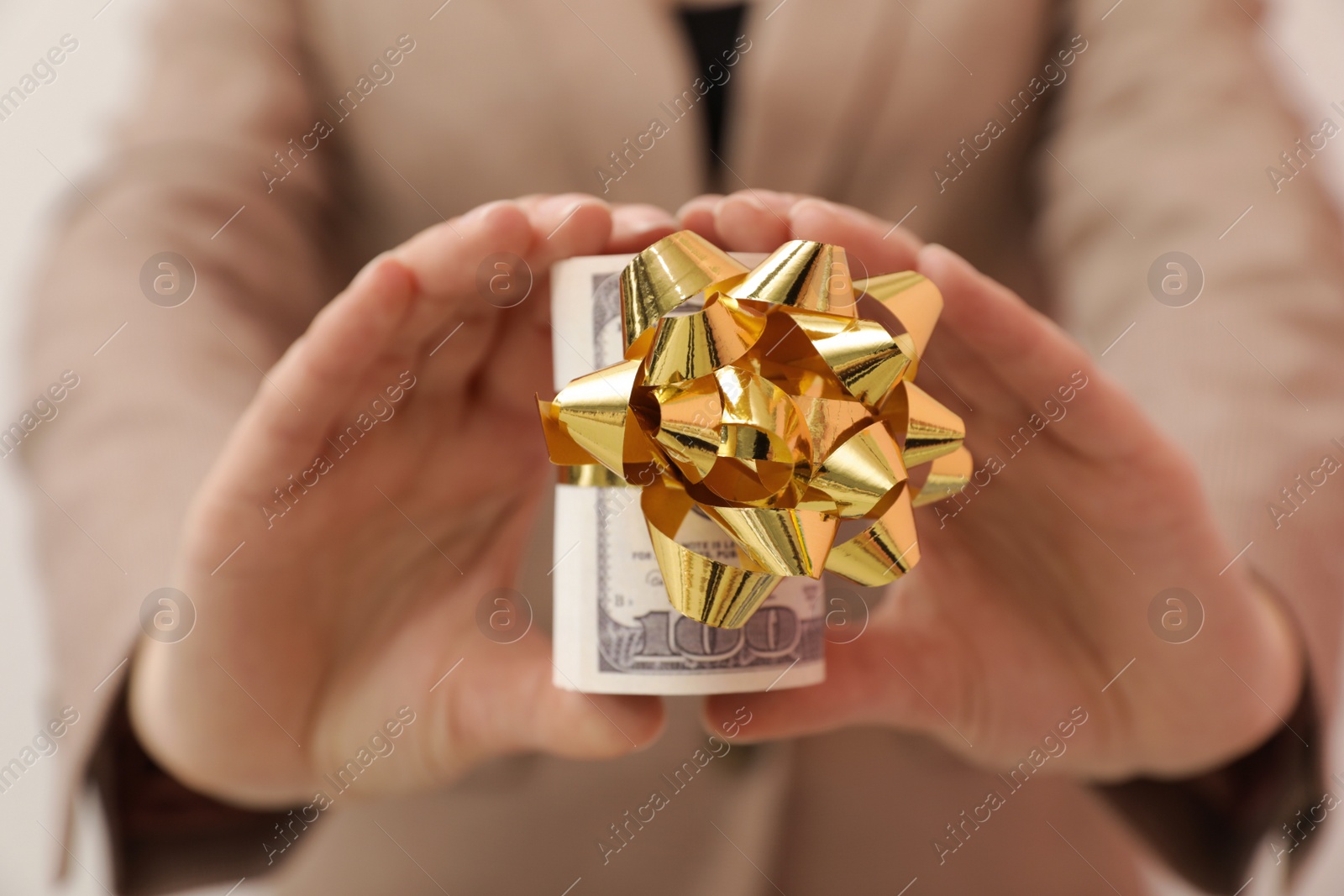 Photo of Woman holding bundle of dollars tied with ribbon, closeup