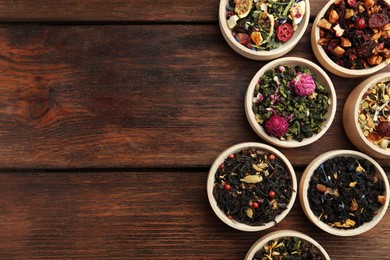Photo of Different kinds of dry herbal tea in bowls on wooden table, flat lay. Space for text