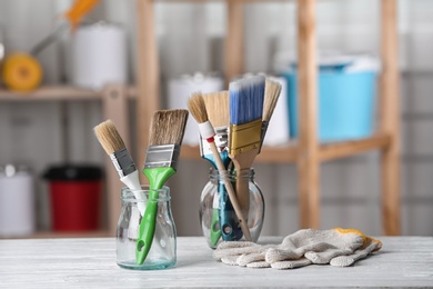 Glass jars with paint brushes and gloves on table in workshop