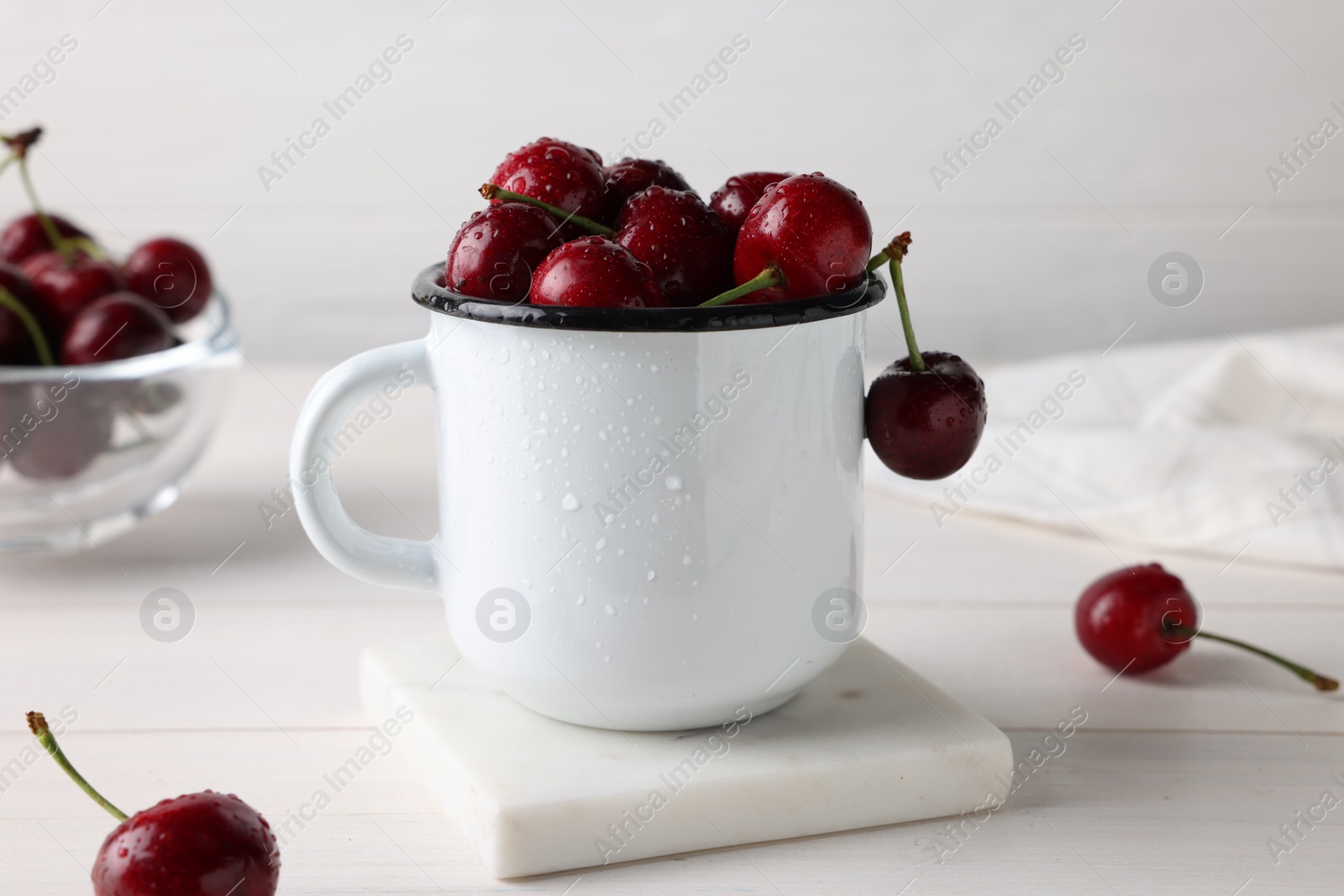 Photo of Fresh ripe cherries with water drops on white wooden table, closeup