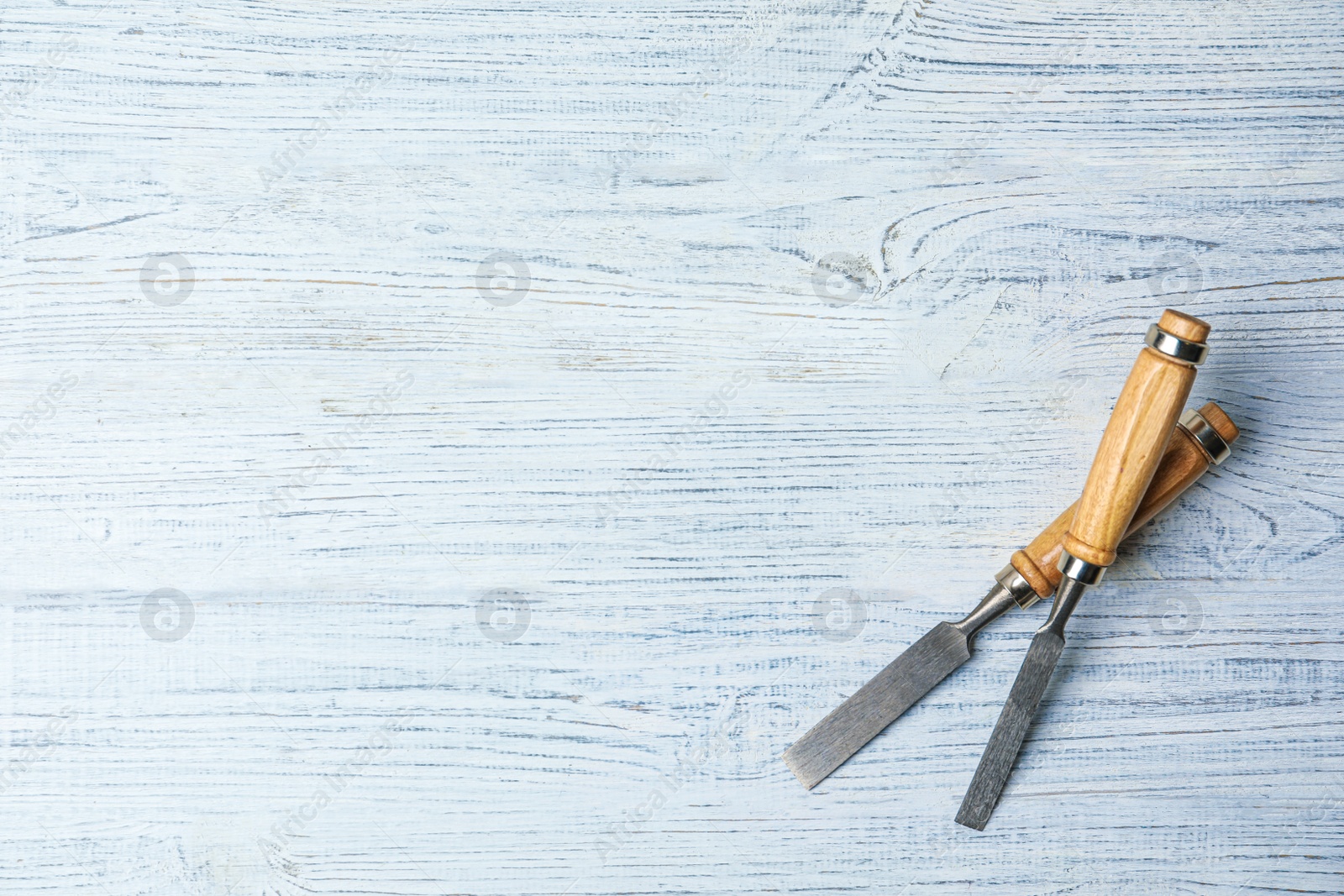 Photo of Modern chisels on white wooden background, flat lay with space for text. Carpenter's tools