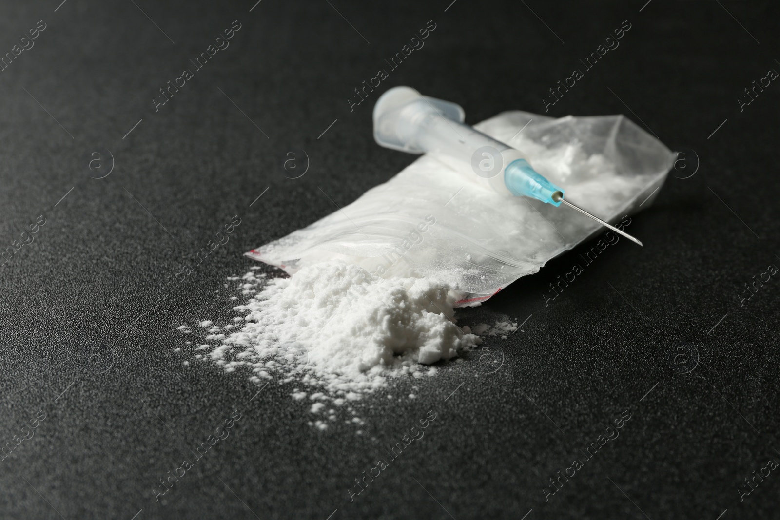 Photo of Cocaine in plastic bag and syringe on dark background