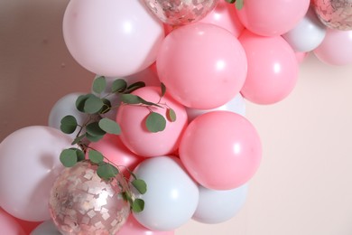 Photo of Beautiful composition with balloons and green leaves on beige background, closeup