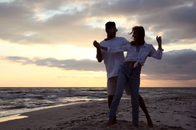 Happy couple dancing on beach at sunset