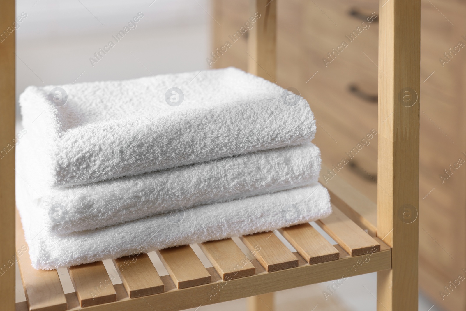 Photo of Stacked bath towel on wooden shelf indoors