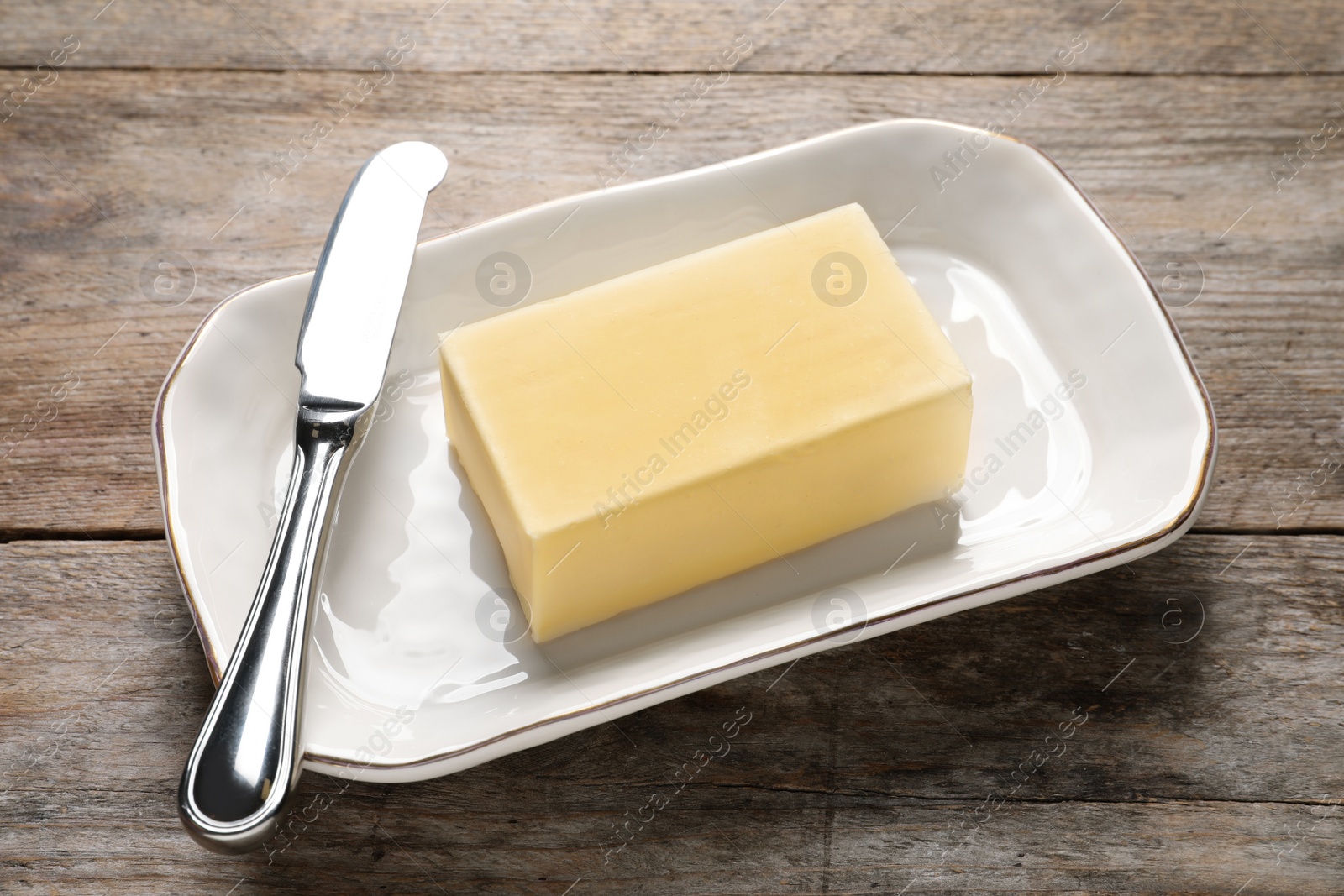 Photo of Dish with fresh butter and knife on wooden table