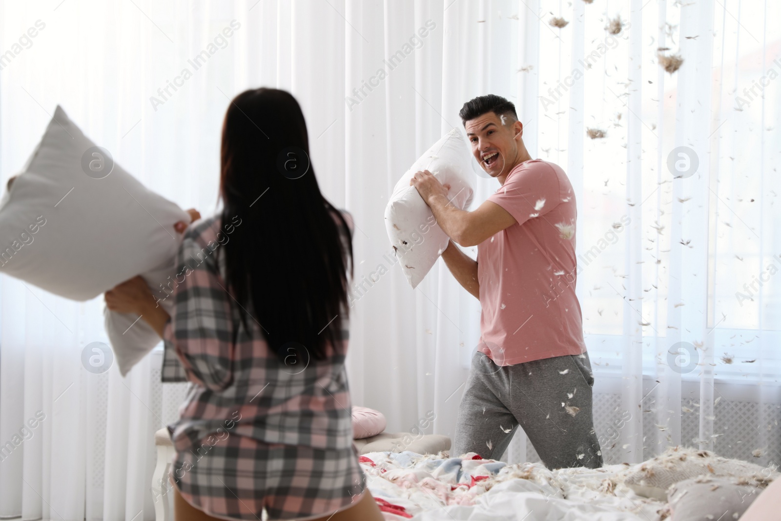 Photo of Happy couple having pillow fight in bedroom