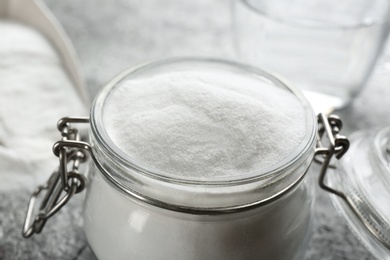 Photo of Baking soda in glass jar on table, closeup view