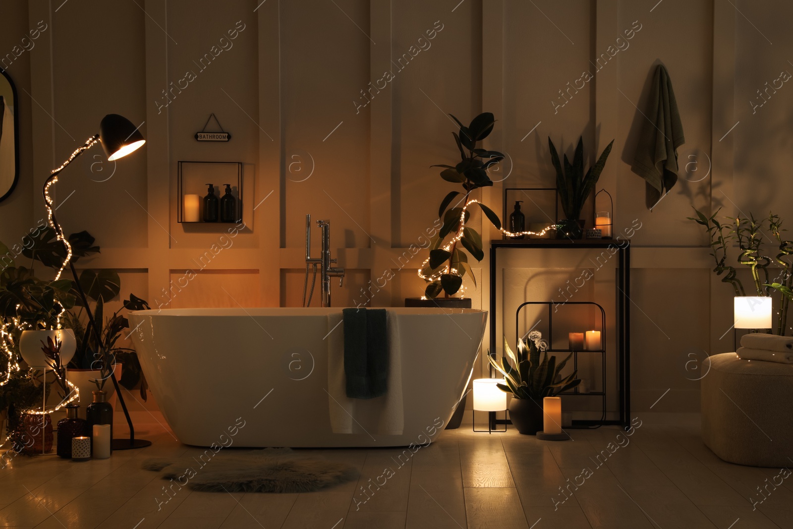 Photo of Stylish bathroom interior with houseplants and string lights. Home design