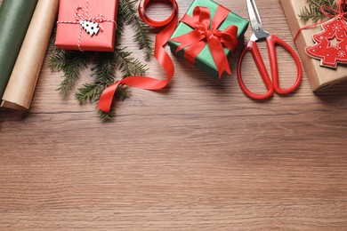 Photo of Flat lay composition with beautiful Christmas gift boxes and wrapping paper on wooden table. Space for text