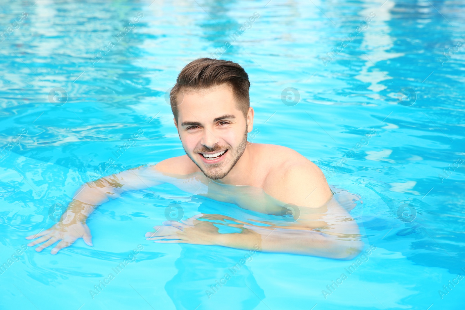 Photo of Young handsome man in swimming pool on sunny day