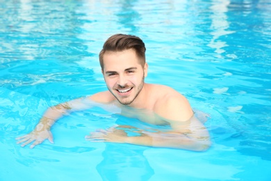 Young handsome man in swimming pool on sunny day