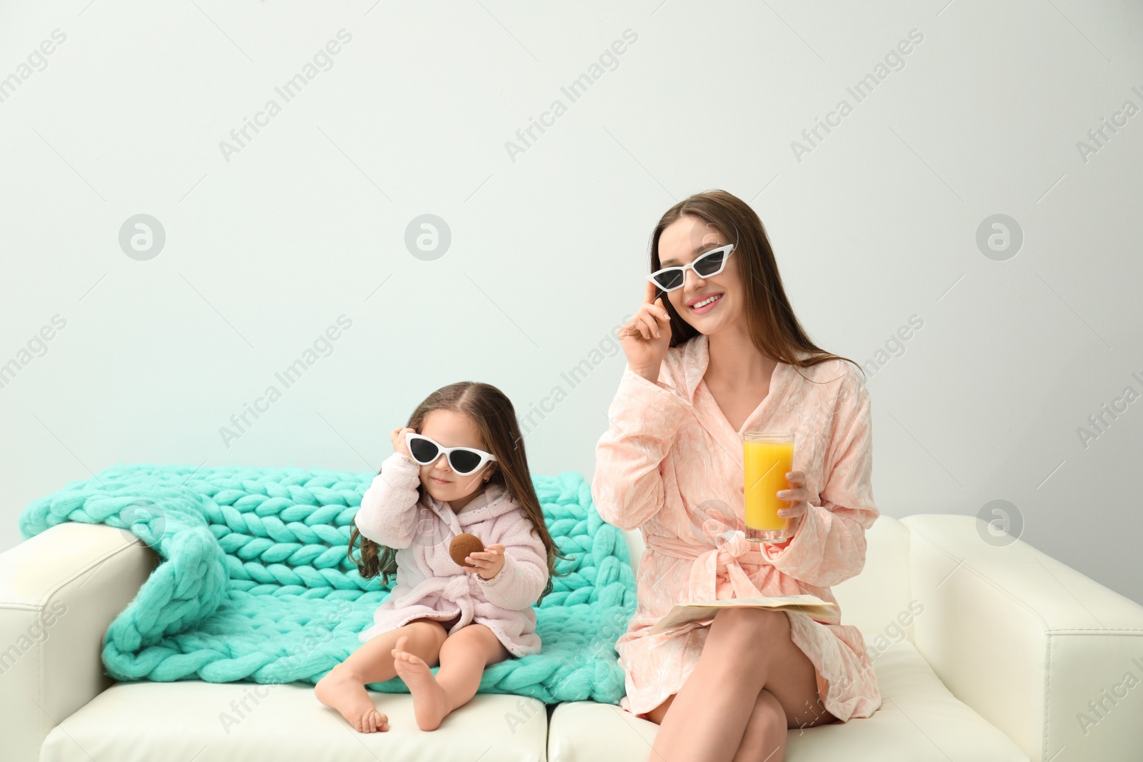 Photo of Mother and daughter in bathrobes sitting on sofa