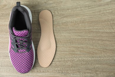 Photo of Orthopedic insole near shoe on floor, flat lay. Space for text