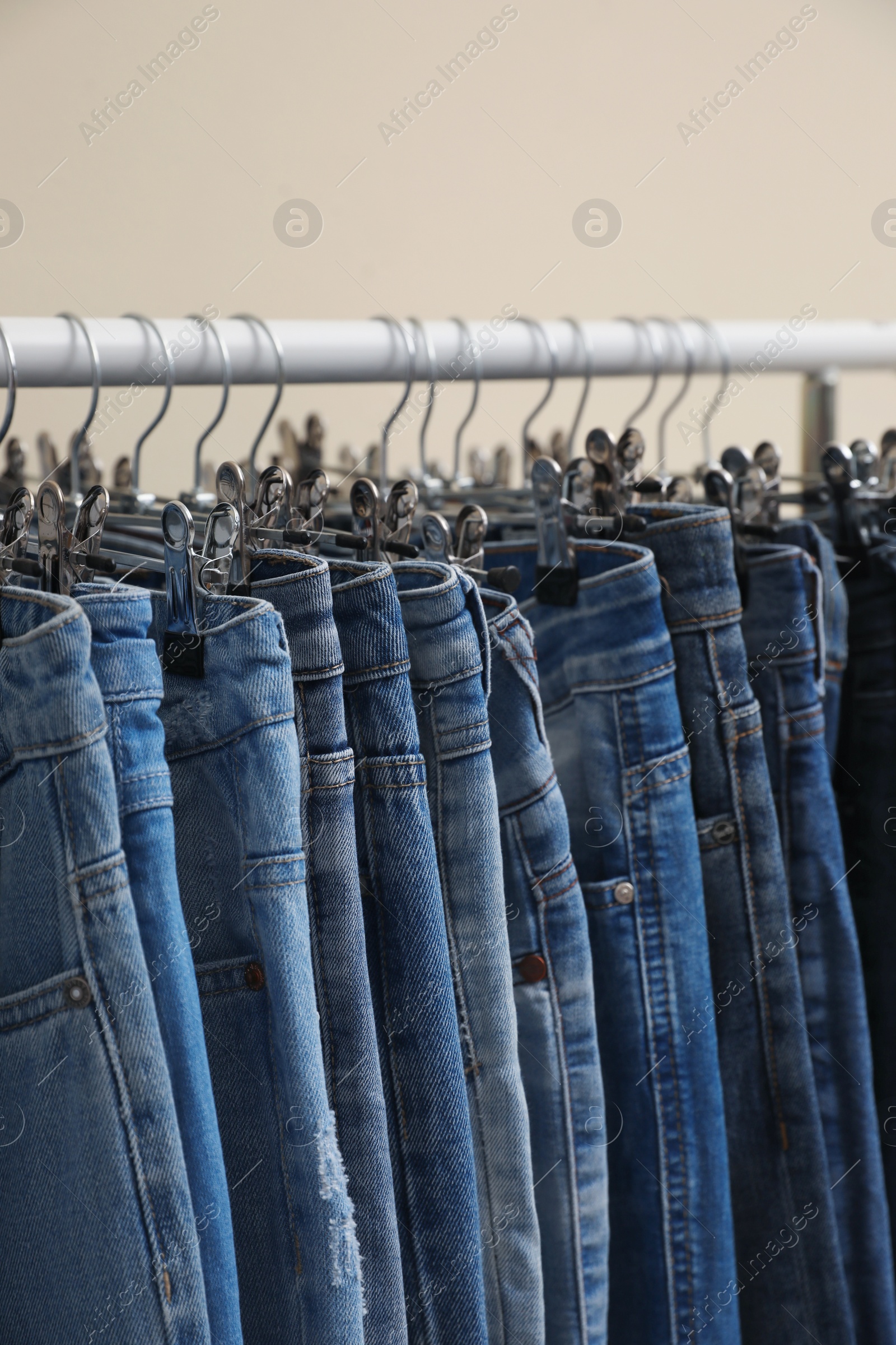 Photo of Rack with stylish jeans on color background, closeup