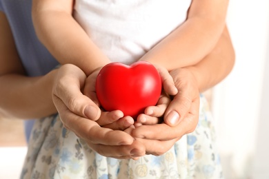 Photo of Adult and child hands holding heart on light background, closeup. Family concept