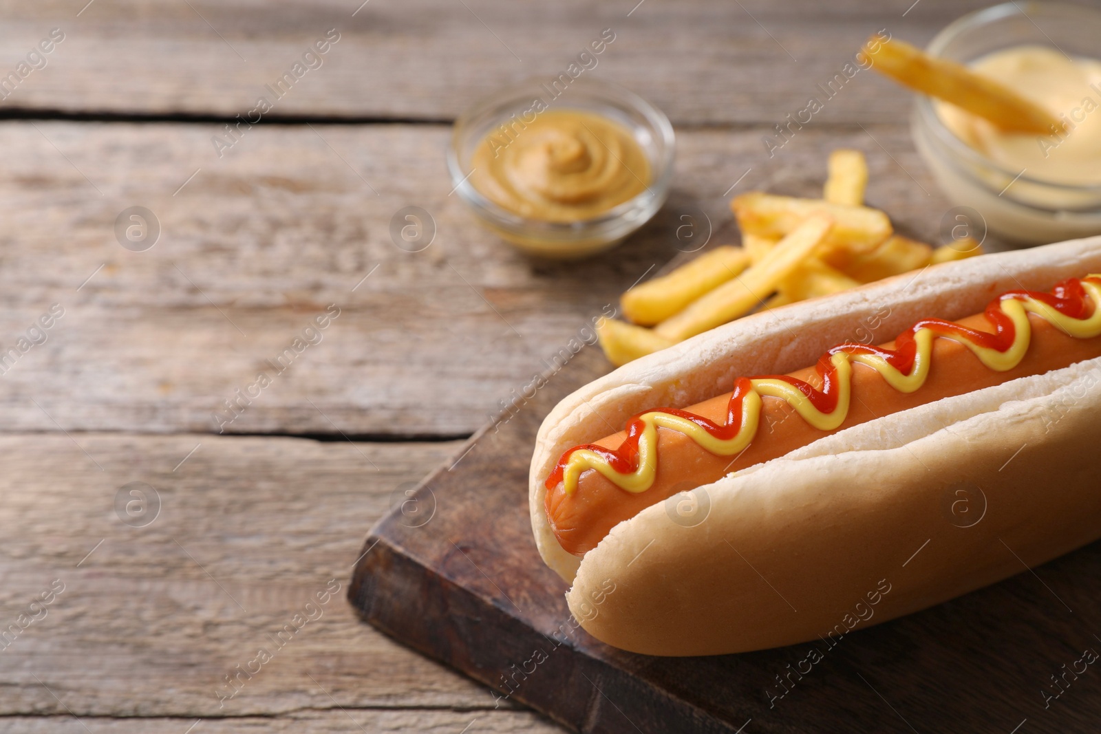 Photo of Delicious hot dog with ketchup and mustard on wooden table, closeup. Space for text