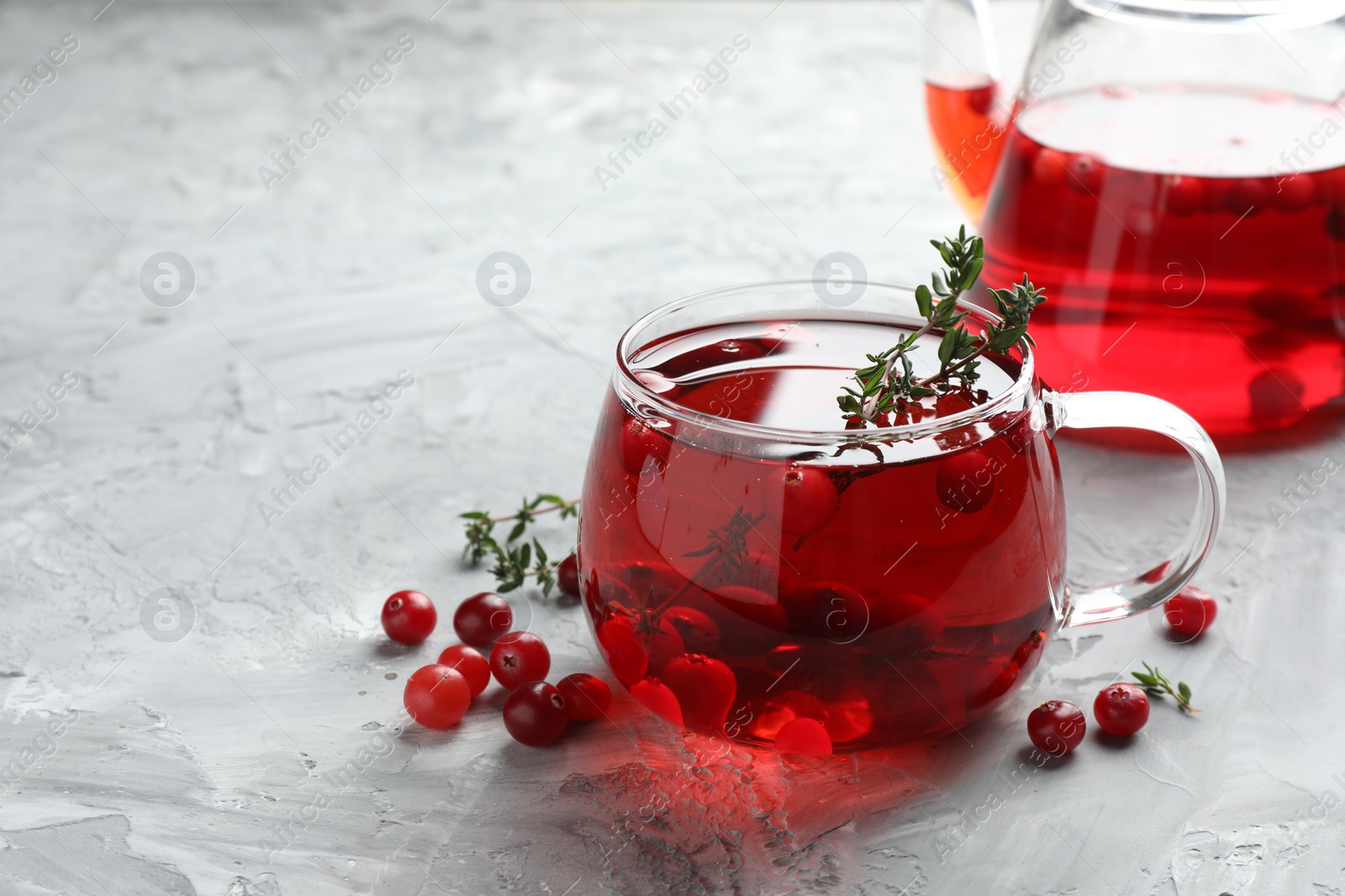 Photo of Delicious cranberry tea with thyme and berries on grey table, closeup. Space for text