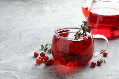 Photo of Delicious cranberry tea with thyme and berries on grey table, closeup. Space for text