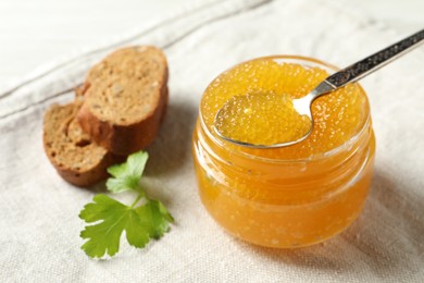 Fresh pike caviar in glass jar, bread and parsley on table