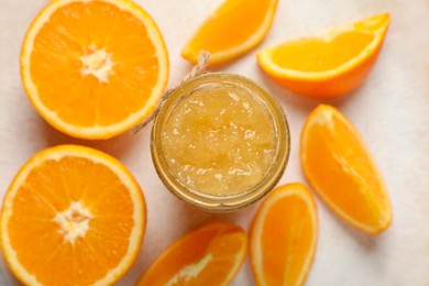 Photo of Jar of delicious orange jam and fresh fruits on plate, flat lay