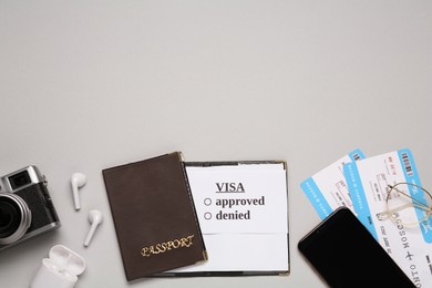 Flat lay composition with passport, tickets and earphones on light grey background, space for text. Visa receiving