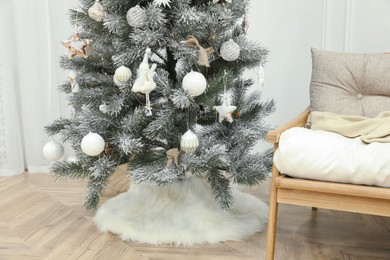 Beautiful decorated Christmas tree with skirt in room