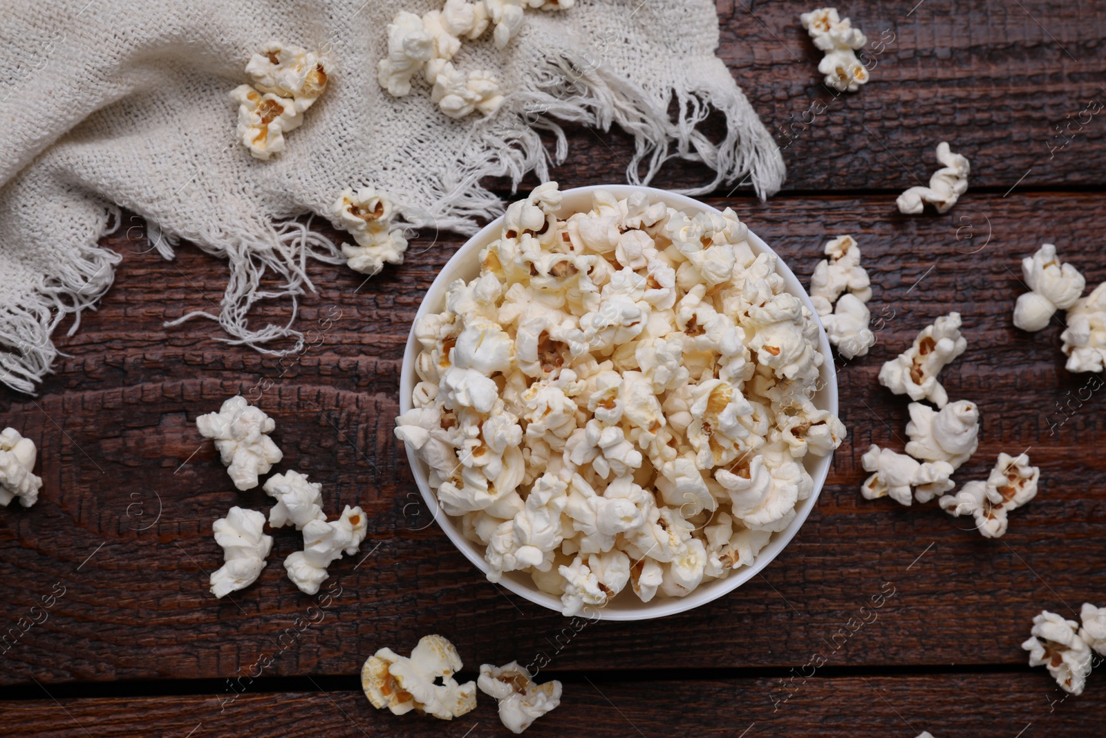 Photo of Bowl of tasty popcorn on wooden table, flat lay