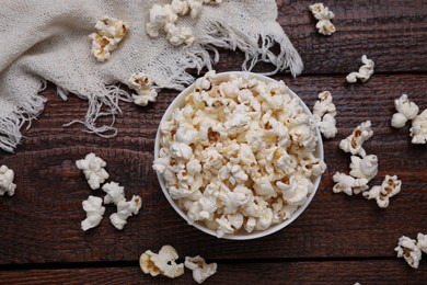 Bowl of tasty popcorn on wooden table, flat lay