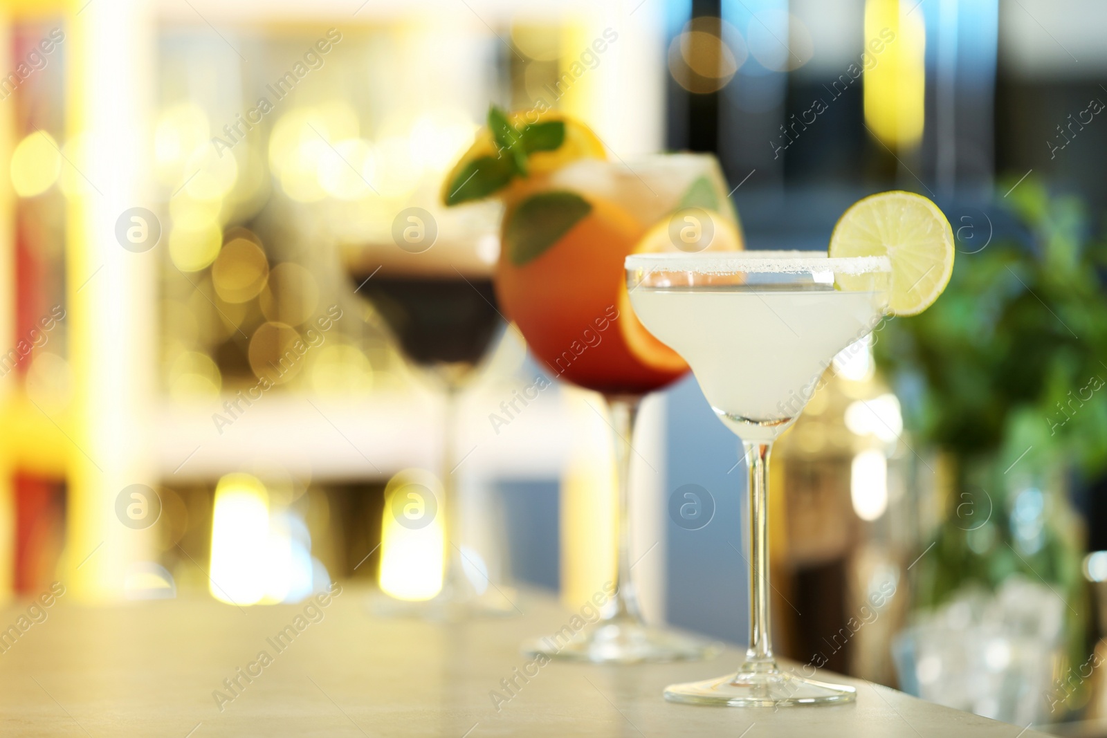 Photo of Row of different fresh alcoholic cocktails on bar counter