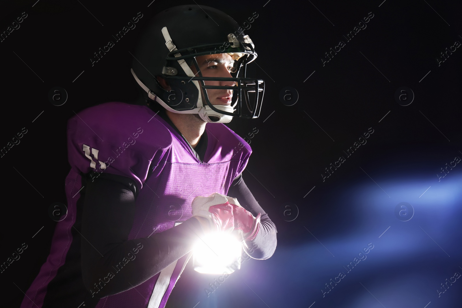 Photo of American football player wearing uniform on dark background. Space for text