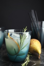 Photo of Tasty refreshing pear cocktail with rosemary on table