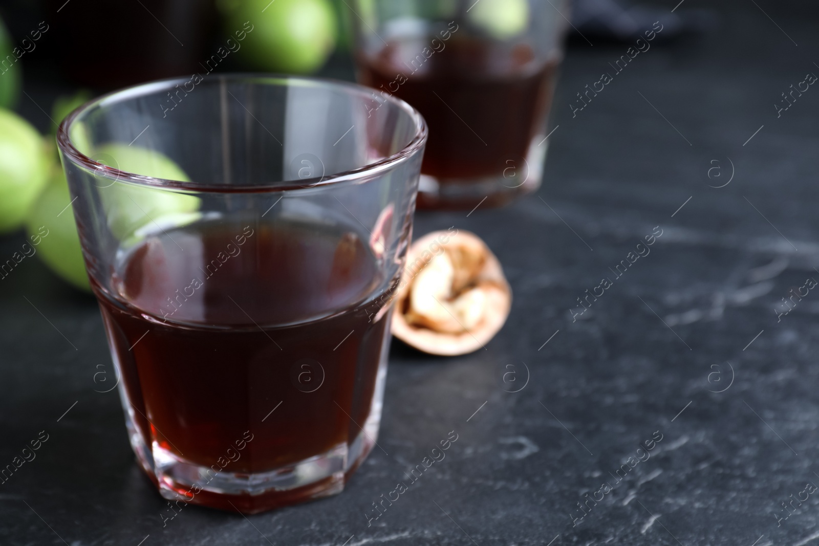 Photo of Delicious liqueur and fresh walnuts on black table, closeup. Space for text