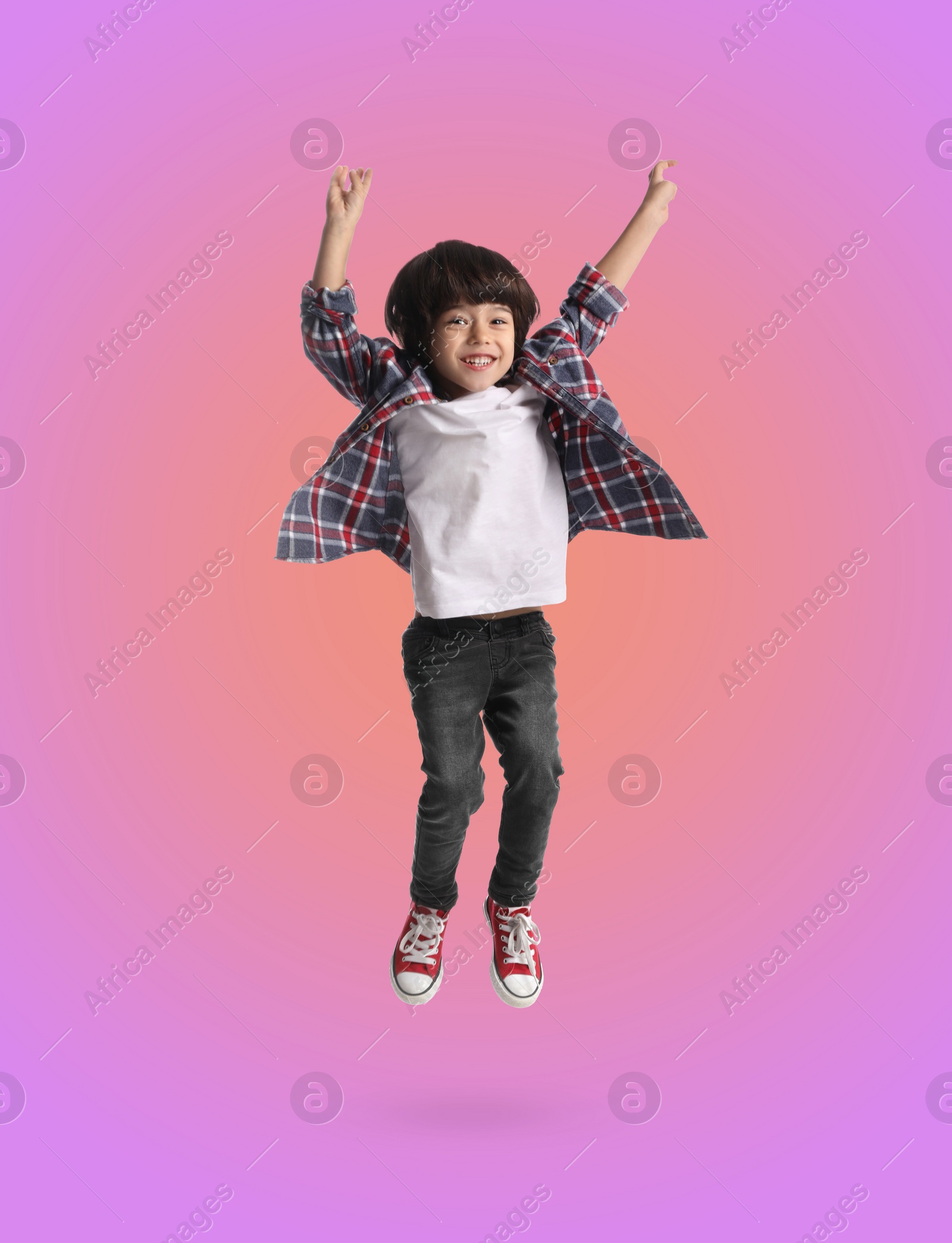 Image of Happy boy jumping on color gradient background