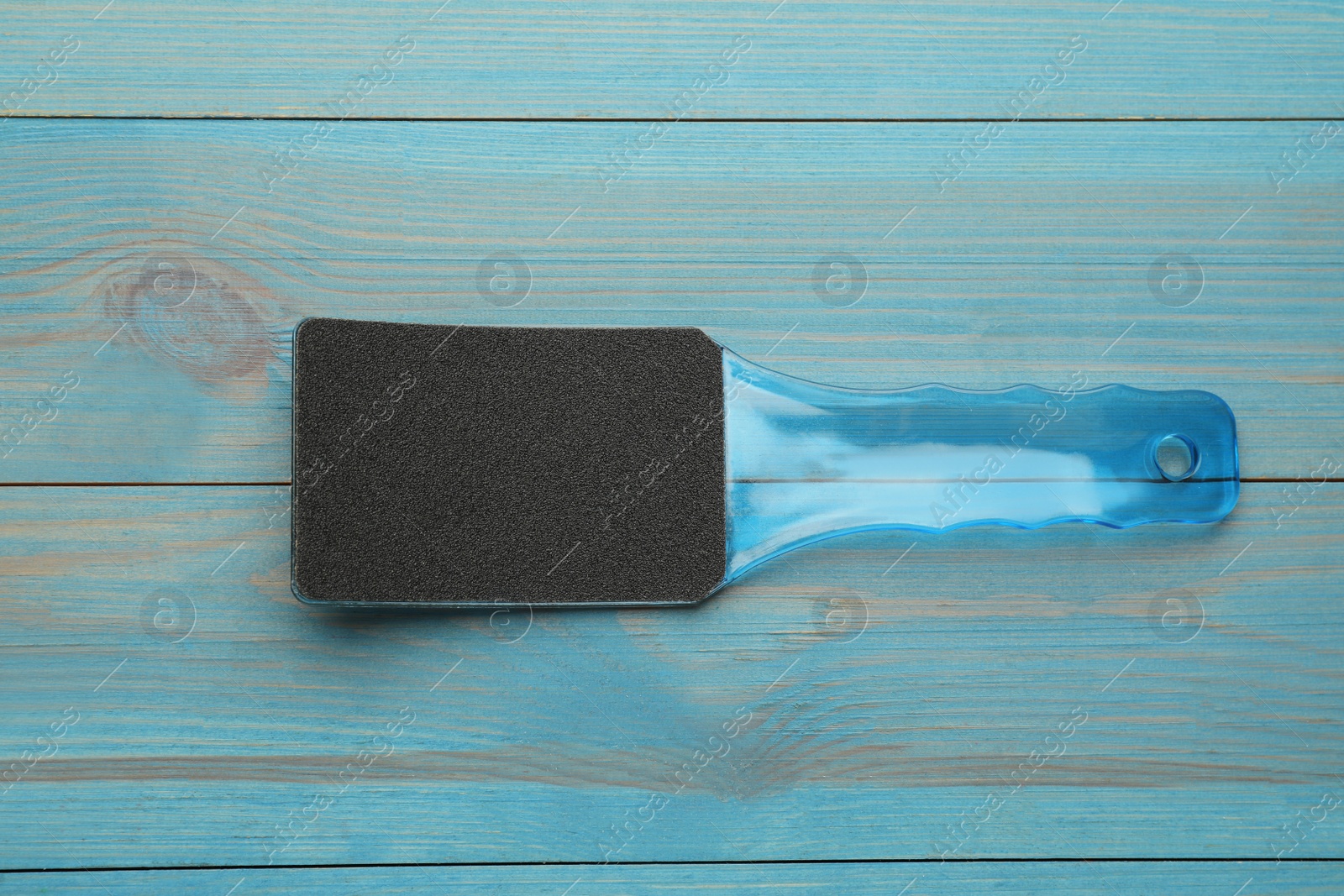 Photo of Foot file on light blue wooden table, top view. Pedicure tool