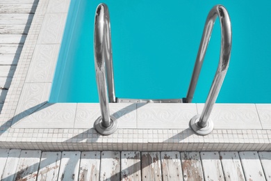 Modern swimming pool with ladder at resort