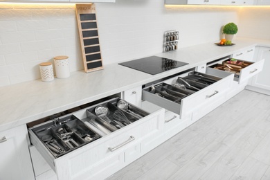 Open drawers with different utensils in kitchen