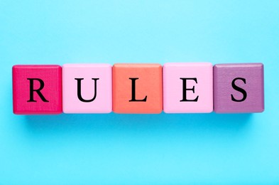 Photo of Word Rules made of colorful cubes with letters on light blue background, flat lay