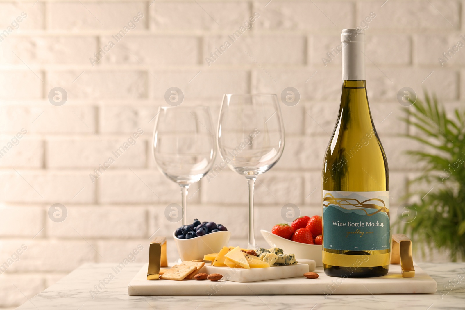 Photo of Bottle of wine, glasses and delicious snacks on white marble table