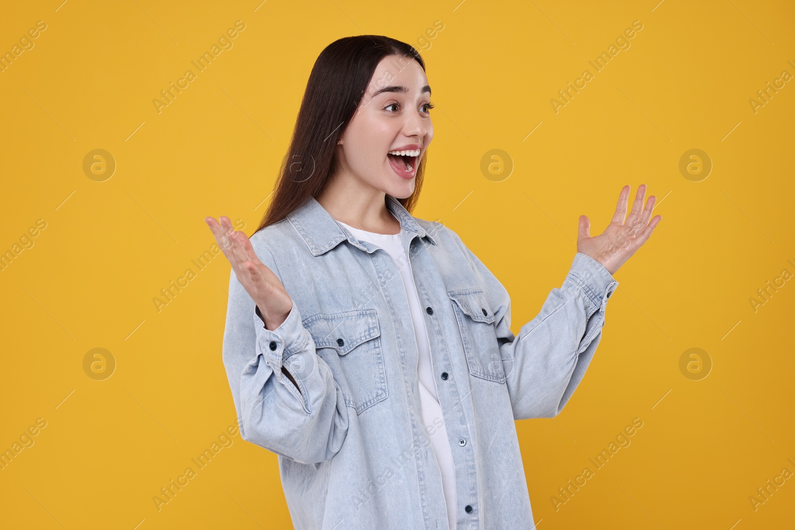 Photo of Portrait of happy surprised woman on orange background