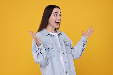 Portrait of happy surprised woman on orange background