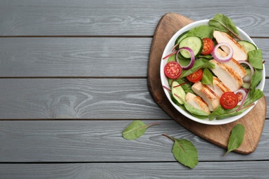 Photo of Delicious salad with chicken and vegetables on grey wooden table, flat lay. Space for text
