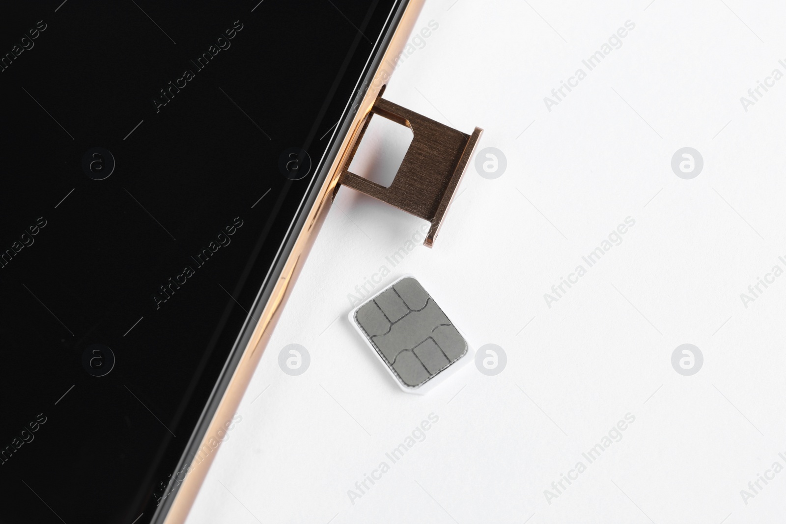 Photo of SIM card and mobile phone on white table, closeup