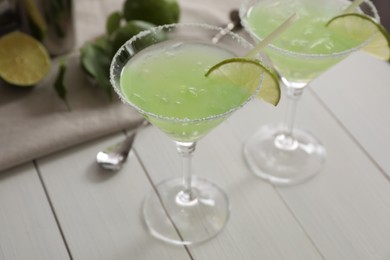 Delicious Margarita cocktail in glasses and lime on white wooden table