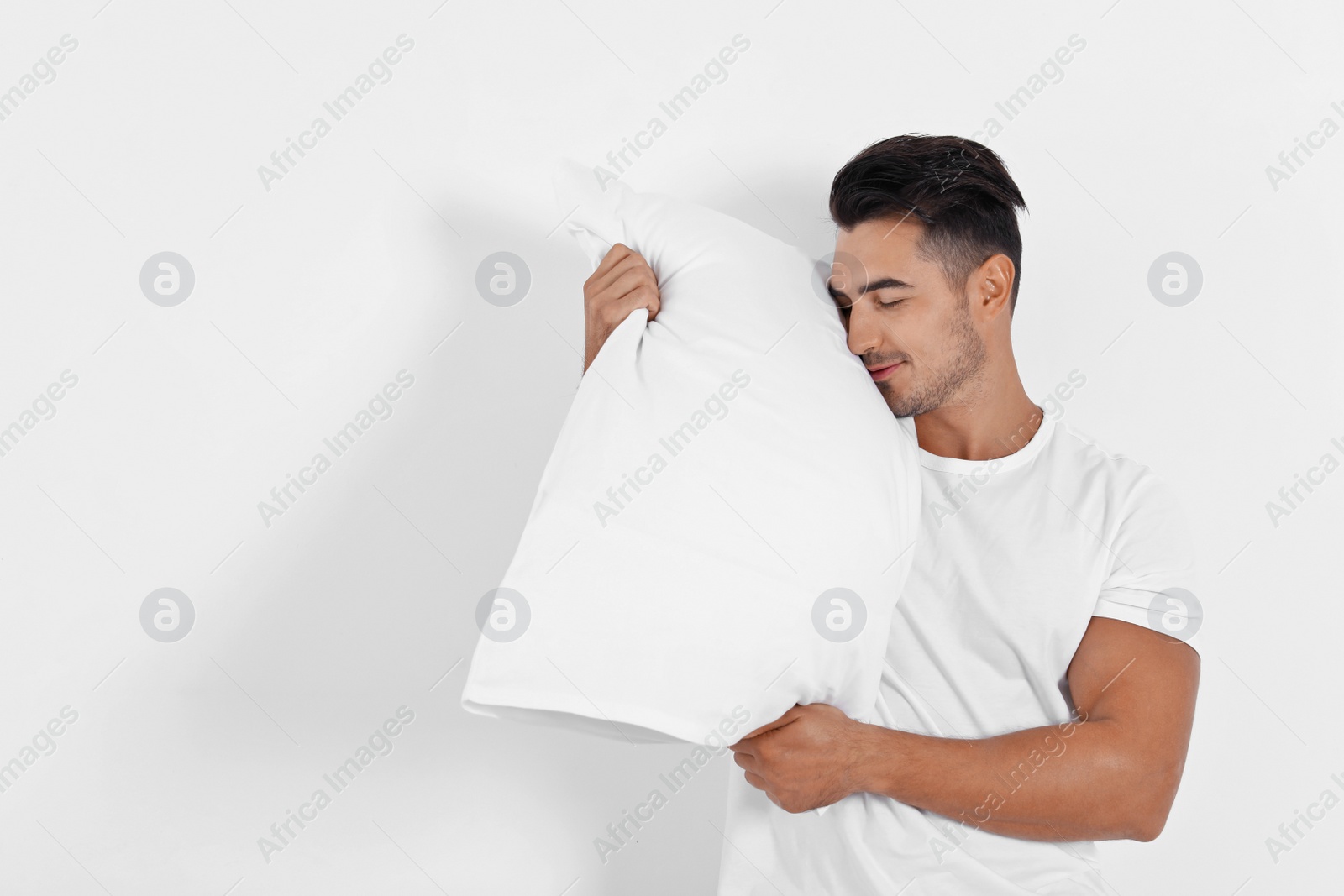 Photo of Young man with soft pillow on white background